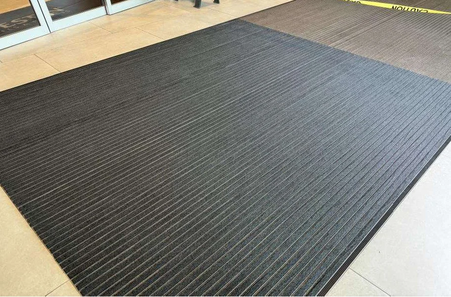 Hotel entrance with the original brown carpet inserts on the right and the new anthracite carpet inserts on the left